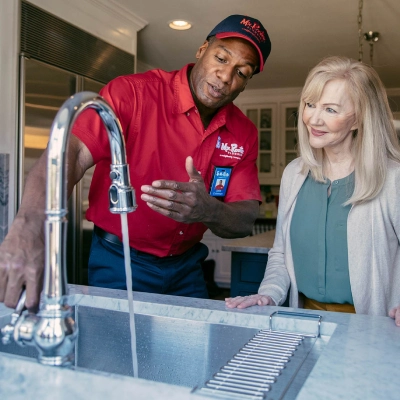 Mr. Rooter professional showing customer a fixed faucet.