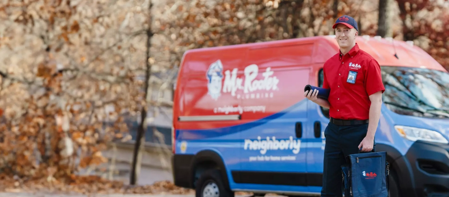 Mr. Rooter technician standing beside a branded van.