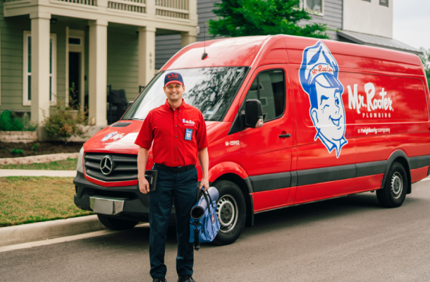 Mr. Rooter professional standing beside a branded van.