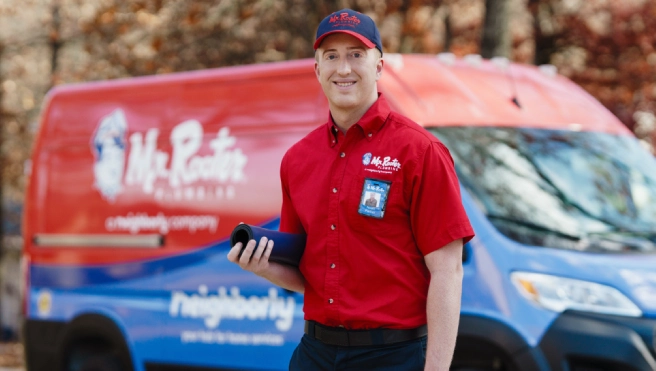 Mr. Rooter professional standing beside a branded van.