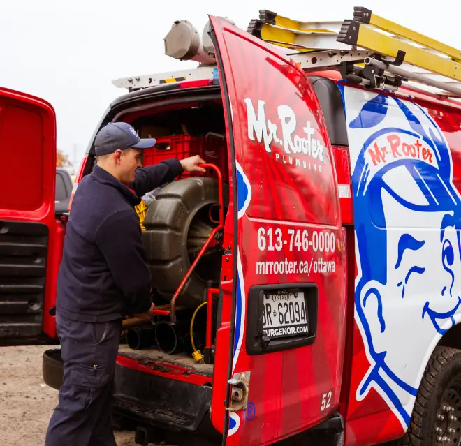 Mr. Rooter technician unloading equipment from the back of a branded van.