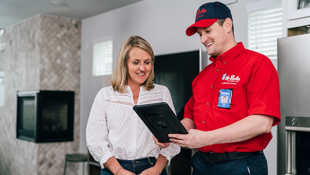 Mr. Rooter professional going over service options on a tablet with a customer.