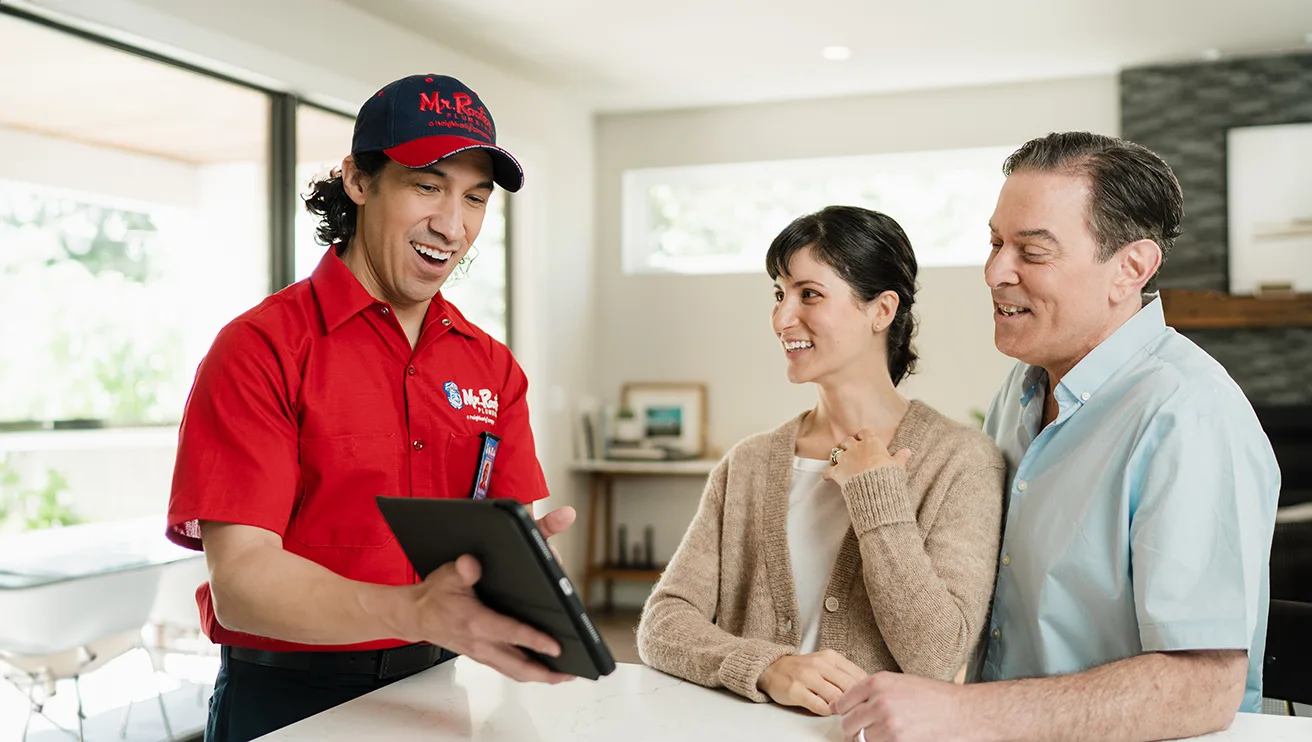 Mr. Rooter technician showing two customers service options on a tablet.