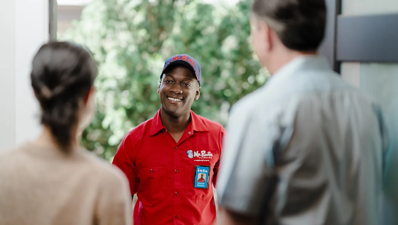 Two customers greeting a Mr. Rooter technician at their home's front door.