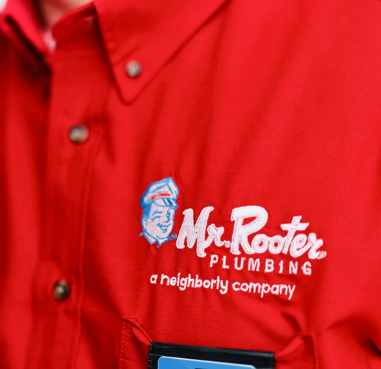 Close up image of a Mr. Rooter logo on a red work shirt.