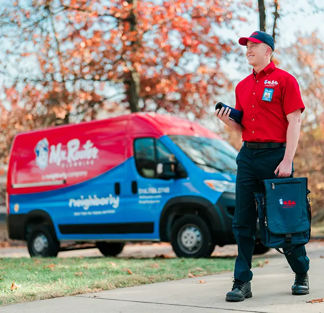 Mr. Rooter technician walking up to a home with a branded van in the background.