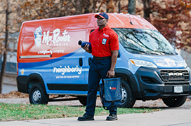 Mr. Rooter professional standing by a branded van.