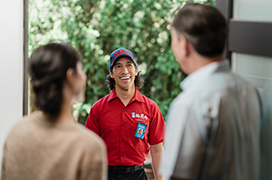 Two customers greeting a Mr. Rooter technician at their door.