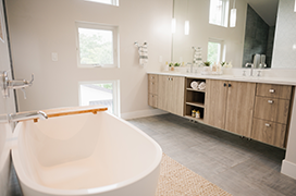 Image of a modern bathroom with a large soaking tub and floor to ceiling windows.