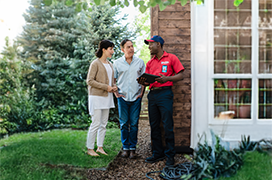 Two customers speaking with a Mr. Rooter technician outside of their home.