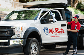 Mr. Rooter professional standing next to a white branded work truck.