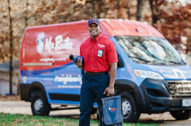 Mr. Rooter professional standing beside a branded van.