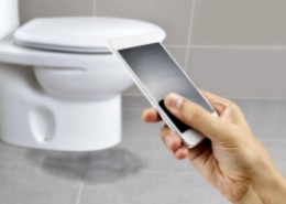 Customer holding a cell phone with a toilet in the background.