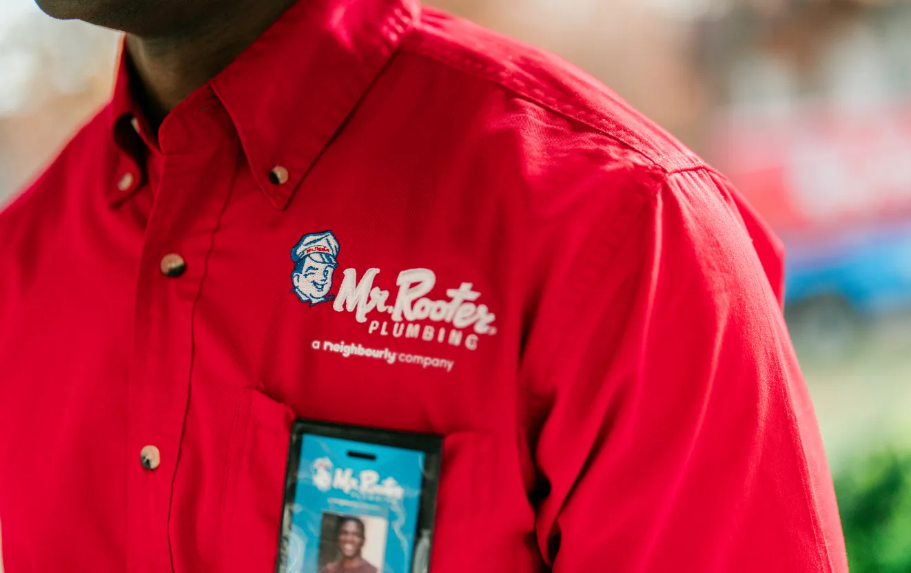 The Mr. Rooter logo on the red polo shirt of a technician.