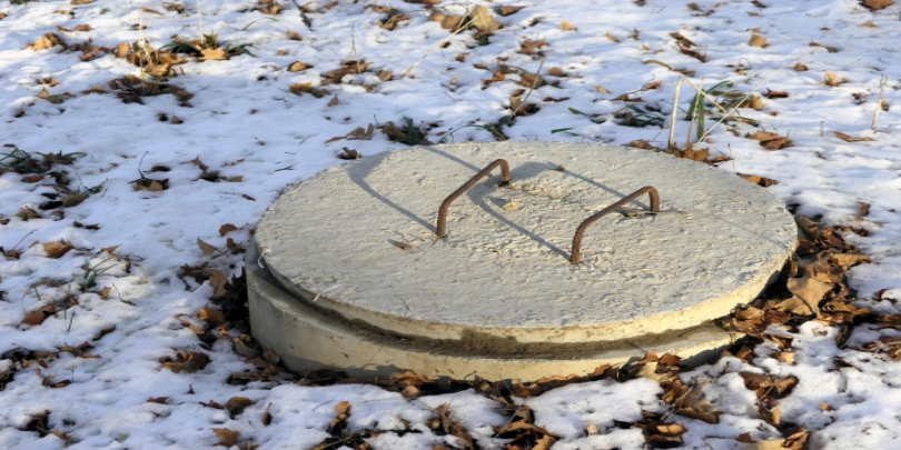 Septic tank in rural area during winter with snow covering the ground