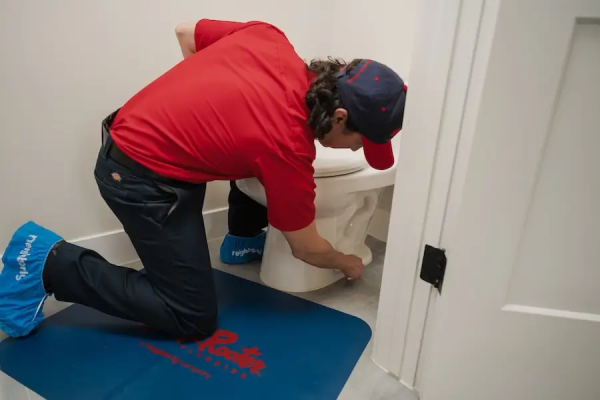 A Mr. Rooter Plumbing&reg; professional installing a new toilet in a residential bathroom.