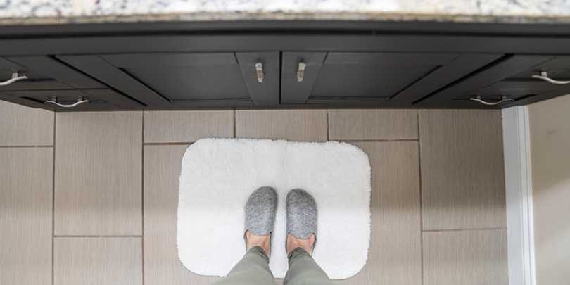 First person view of someone standing on mat in front of a sink