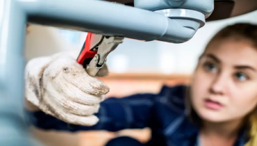 Plumber fixing a kitchen sink with plumbing tools.