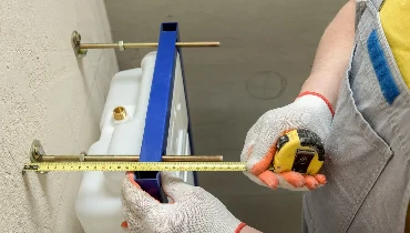 Calgary plumber measuring distance to properly perform toilet replacement.