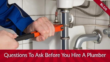 Someone holding an orange wrench by a pipe with banners reading 